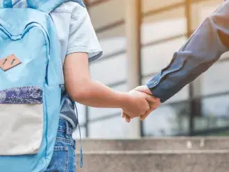 child with backpack walking into school