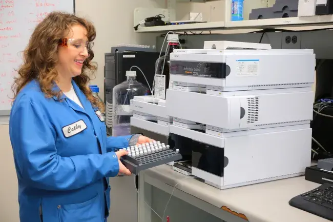 a woman in a lab coat places tubes in a tray