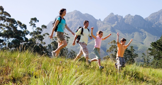 A family of four hike in an alpine meadow.